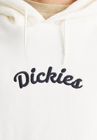 Sudadera blanca con un logotipo negro bordado de "Dickies". Tejido suave con un diseño clásico y capucha ajustable con cordón.