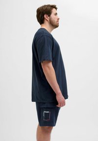Herre navy blå bomulds T-shirt og shorts sæt. T-shirten har en afslappet pasform; shortsene har et patch logo og sidelommer for praktisk anvendelse.
