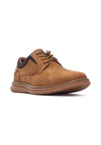 Zapato de ante marrón con punta redonda, diseño de cordones, detalles en azul oscuro contrastante y suela de goma texturizada.