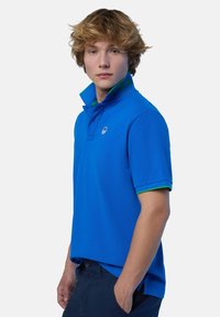 Polo blu con dettagli verdi su colletto e maniche, con un logo sul petto. Realizzato in cotone, ha una vestibilità classica e maniche corte.