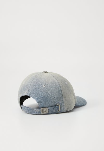 Casquette de baseball en denim avec une visière incurvée, couleur bleu clair, texture délavée, sangle à l'arrière pour ajustement, et un accent de logo en métal.