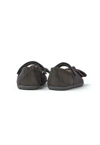 Scarpe in suede marrone scuro con una texture morbida, punta arrotondata e suole piatte. Presentano una fascia sul retro e un fiocco decorativo sul davanti.