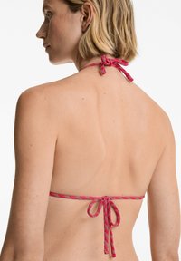 Rdeče in bele prožne bandeau bikini zgornji del z obliko halter vratu, ki ima nastavljive vezi na hrbtu in gladko teksturo tkanine.