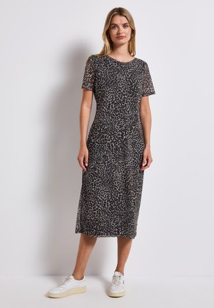 Leopard print midi dress in soft fabric, featuring short sleeves, a round neckline, and a form-fitting silhouette. Styled with white sneakers.