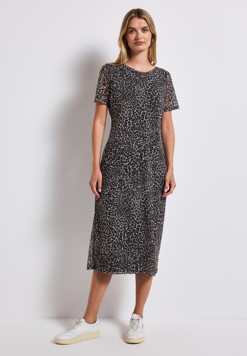 Leopard print midi dress in soft fabric, featuring short sleeves, a round neckline, and a form-fitting silhouette. Styled with white sneakers.