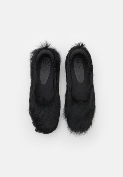 Black slip-on shoes with a soft, fuzzy texture and rounded toe design. Features high faux fur around the upper edges.