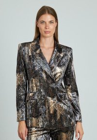 Blazer de estampado de serpiente metálico con un ajuste entallado, solapas afiladas y cierre de doble botón. Los colores incluyen tonos de negro, oro y bronce.