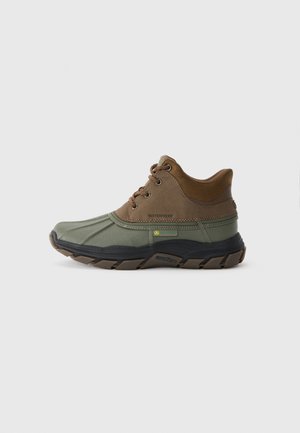 Chaussures imperméables marron et vert avec un dessus texturé, un col rembourré et une semelle noire robuste avec des crampons prononcés.