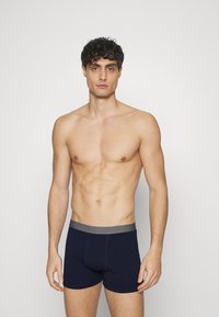 Boxeri navy blue cu un elastic gri, fabricați dintr-un material elastic, având un design ajustat și cusături plate pentru confort.