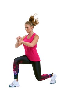 Pink tank top, black leggings with colorful geometric patterns, white sneakers. Subject in a lunge position, engaged in an athletic stance.