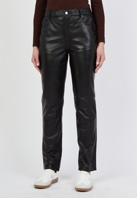 Zwarte leren broek met een strakke, gladde textuur, aansluitend ontwerp en voorzakken. Heeft een knoop- en ritssluiting bij de taille.