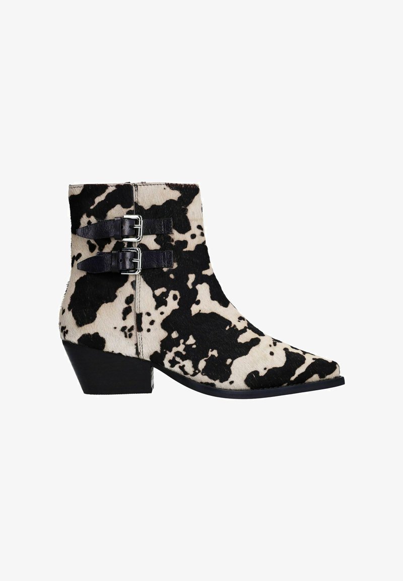Bottes ankle en cuir de vache avec un motif tacheté noir et blanc, dotées de deux sangles noires et de boucles argentées, à bout effilé et à talon bas.