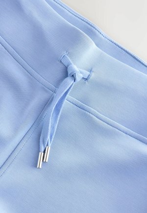 Lichtblauwe stof met een gladde structuur, voorzien van een trekkoorddetail met zilverkleurige oogjes en platte naden. Subtiel en uniform ontwerp.