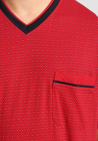 Rood kortemouwen shirt met een diamanten patroon, V-hals ontwerp, zwarte accent rond de kraag en een borstzak aan de linkerkant met stiksel details.