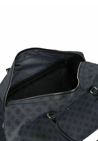 Sac de sport synthétique noir avec une ouverture zippée. Intérieur doublé de tissu foncé avec un motif de logo en répétition. Deux poignées incluses.