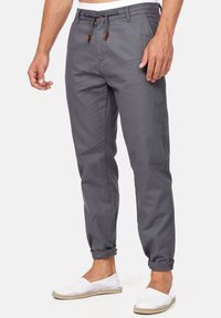Pantaloni cargo grigi elasticizzati con vita regolabile, vestibilità affusolata, caviglie con risvolto e dettagli hardware marroni a contrasto. Design casual.