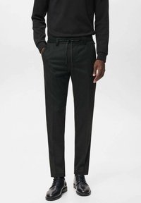 Pantaloni negri, ajustați, cu croi drept, talie cu șnur și textură elegantă. Purtați cu pantofi negri și un pulover asortat.