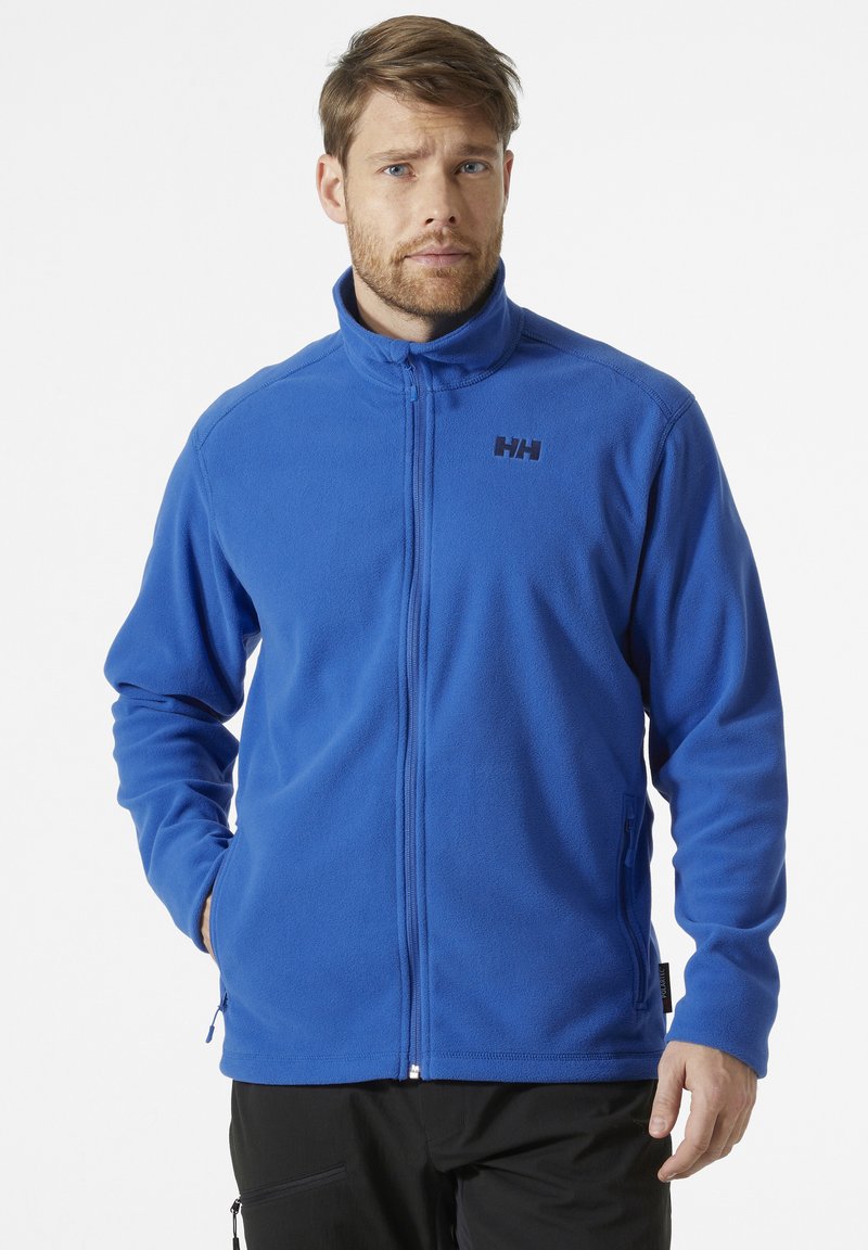 Blauwe fleecjas met hoge kraag, ritssluiting, elastische manchetten en logo op de borst. Voorzien van zijzakken en een soepele textuur.