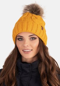 Bright yellow knitted beanie with a textured pattern and a faux fur pom-pom on top. Includes a leatherette accent tag on the side.