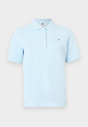 Světle modrá polo košile s krátkým rukávem, límečkem, čtyřmi knoflíky a malým vyšitým logem na levé straně hrudi.