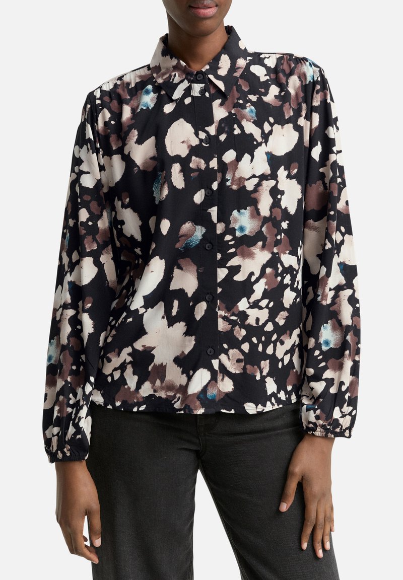 Camisa negra de botones con un patrón floral abstracto en beige, marrón y azul, de manga larga y corte relajado.