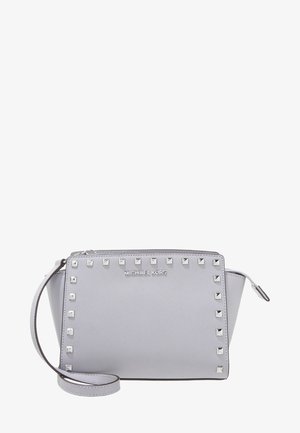 Lysegrå Michael Kors skuldertaske med sølvfarvede firkantede nitter langs fronten og en aftagelig strop.