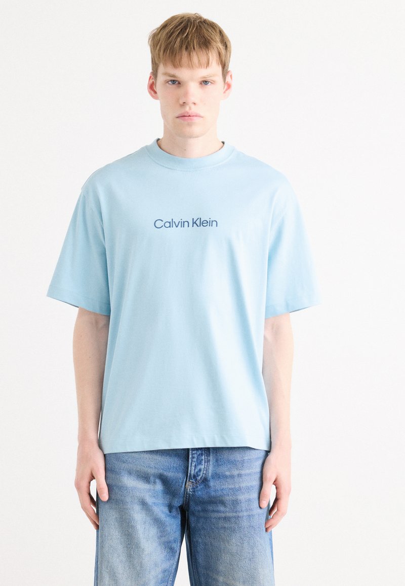 Lys blå bomulls t-skjorte med rund hals og korte ermer. Har en marineblå "Calvin Klein" logo trykket på forsiden.