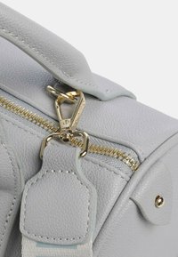 Borsa a tracolla grigia con texture, caratterizzata da una cerniera dorata, accessori in metallo e una tracolla removibile con un accento in pelle.