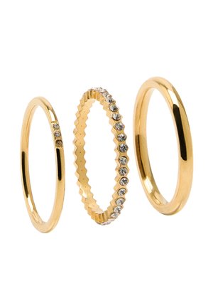 Trzy złote pierścionki ułożone obok siebie: jeden gładki, jeden z małymi diamentami oraz jeden z przezroczystymi kamieniami osadzonymi w ząbkowanym wzorze.