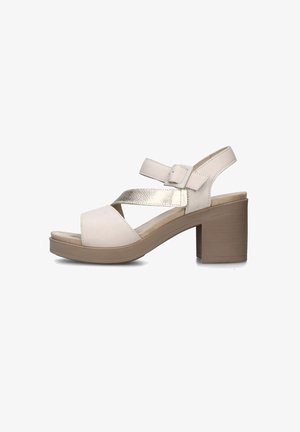 Sandal in pelle beige chiaro con cinturini incrociati e un'accenno metallico. Presenta un tacco a blocco largo e una soletta imbottita per il comfort.