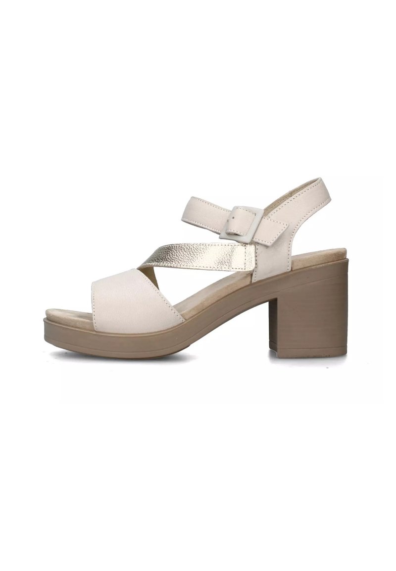 Sandal in pelle beige chiaro con cinturini incrociati e un'accenno metallico. Presenta un tacco a blocco largo e una soletta imbottita per il comfort.