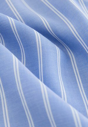 Tessuto blu con sottili strisce diagonali bianche e blu scuro, che mostra una trama dettagliata e pieghe morbide.