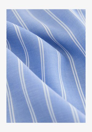 Tessuto blu con sottili strisce diagonali bianche e blu scuro, che mostra una trama dettagliata e pieghe morbide.