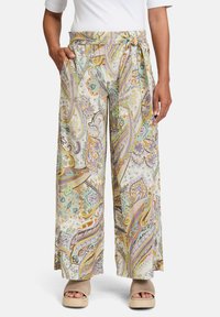 Kalhoty s širokými nohavicemi zdobené vícerozměrnou paisley potiskem v odstínech krémové, fialové, oranžové a zelené. S ozdobným páskem na zavazování a kapsami.