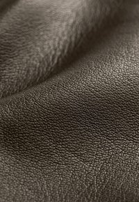 Bruin lederen stof met een getextureerd, stekelig oppervlak. Het materiaal lijkt zacht en buigzaam, met subtiele variaties in tint.