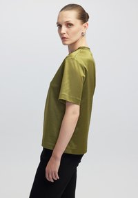 Olijf groene top met korte mouwen en een relaxte pasvorm, gemaakt van een gladde, licht glanzende stof, met een ronde hals en een rechte zoom.