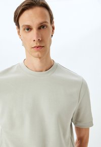 Lys grå crewneck t-shirt lavet af blødt stof med korte ærmer og minimale sømme, med en glat tekstur og afslappet pasform.