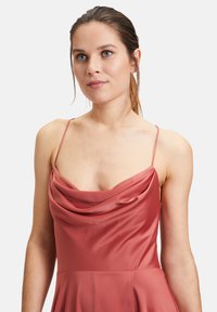 Sukienka bez rękawów z dekoltem w kształcie cowl w miękkim, przybrudzonym różu w satynie. Sylwetka w kształcie litery A z płynącą spódnicą, z cienkimi regulowanymi ramiączkami.