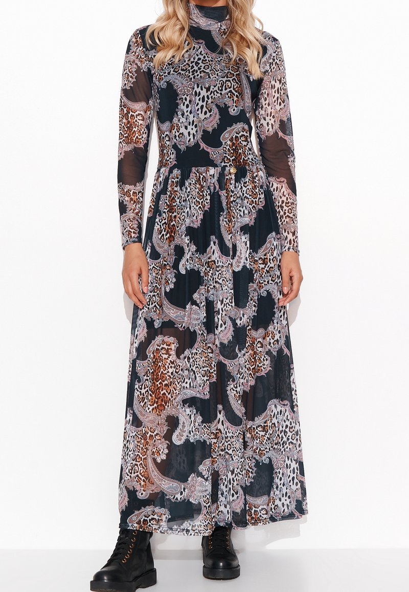 Femme portant une robe longue à manches longues et col montant avec des motifs mélangés léopard et paisley, associée à des bottes de combat noires à lacets.