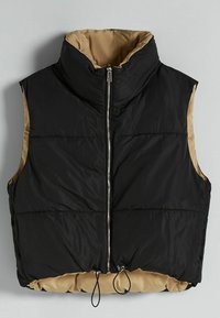 Black puffer vest with a high collar, zip front, and beige lining. Features elastic drawstrings at the bottom and a quilted texture.