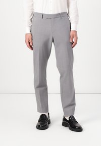 Gray tailored trousers with a smooth fabric, flat front design, tapered legs, and belt loops, paired with black loafers.