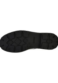 Semelle de chaussure en caoutchouc noir avec un motif de semelle texturé. Présente la marque "GUESS" et une désignation de taille "37" embossée sur la surface.