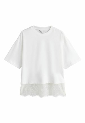 Fehér rövid ujjú póló díszes csipkés alsó szegéllyel. Puha anyagú, kényelmes szabású, kerek nyakkivágással.