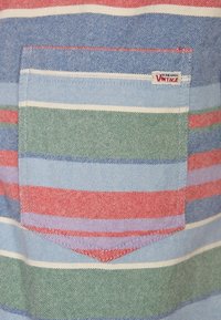 Gestreept shirt met blauw, groen en rood, voorzien van een borstzak; gemaakt van gestructureerde stof; inclusief een vintage merkembleem.