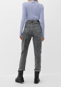 Szare dżinsy z wysokim stanem z efektem sprania, pięcioma kieszeniami i podwiniętymi mankietami. Połączone z miękkim, jasnofioletowym prążkowanym topem z długim rękawem.