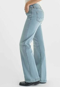 Jeans en denim bleu clair évasés avec une taille haute, des poches avant et des poches arrière cousues présentant un motif distinctif.