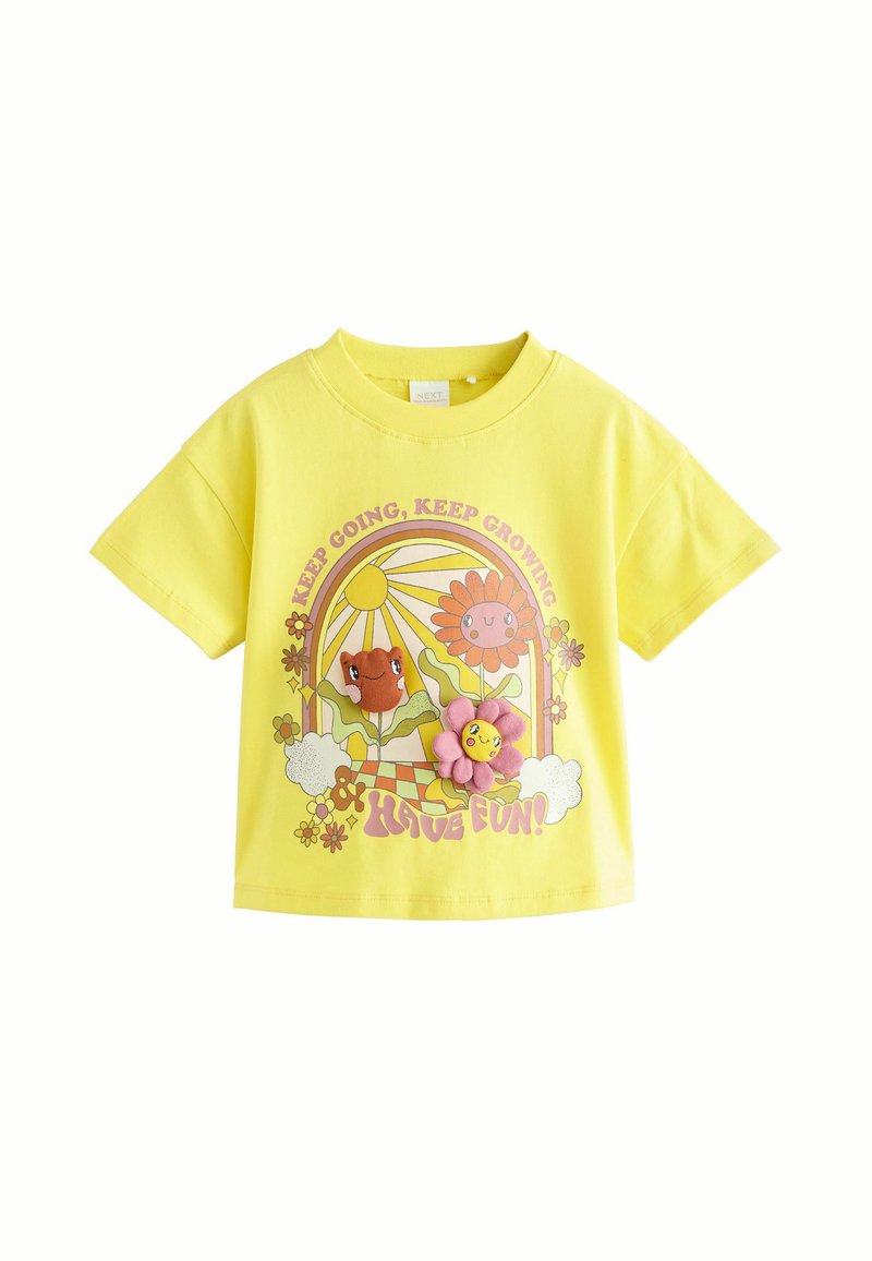 Gul bomulds T-shirt med korte ærmer, der har et farverigt trykt design af blomster, en smilende sol, og teksten "Bliv ved, Bliv ved med at vokse!"