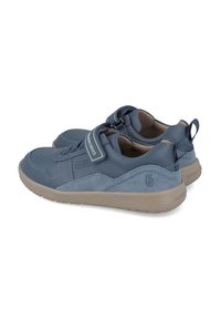 Zapatillas deportivas azules que combinan materiales lisos y de ante, con una cinta de velcro, forma redondeada y suela flexible y texturizada.