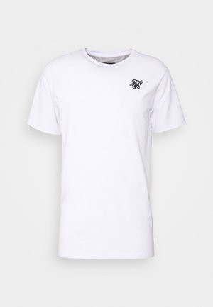 Hvid kortærmet t-shirt med rund hals, forsynet med et lille sort logo på venstre bryst, præsenteret mod en ensfarvet lys baggrund.