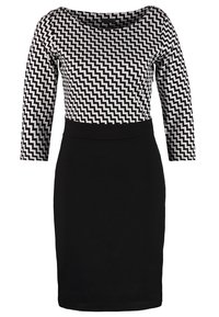 Robe noire avec un haut à motif zigzag noir et blanc, présentant un col bateau et des manches trois-quarts. Finition en tissu lisse.